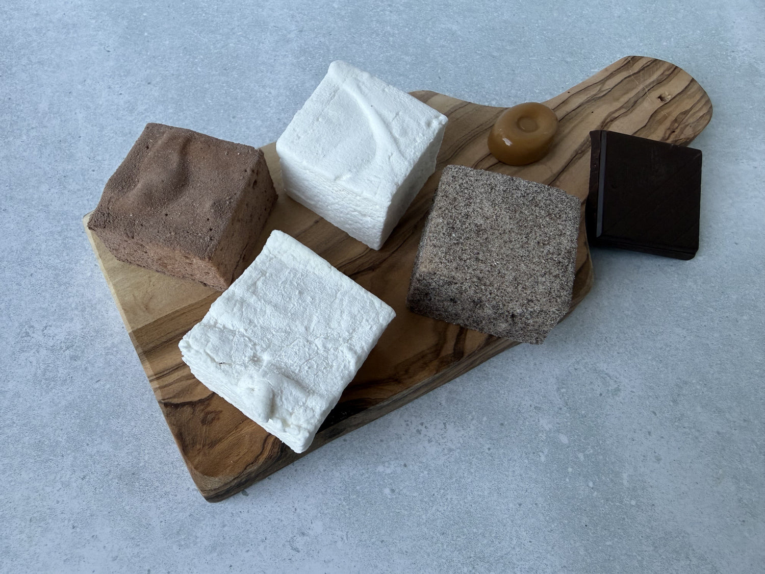 Handcrafted nostalgic marshmallow flavors inspired by classic treats and comforting favorites, arranged on an olive wood serving board.